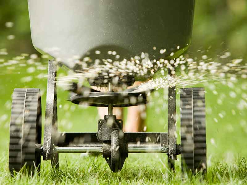 a machine used to fertilize grass being rolled on the lawn