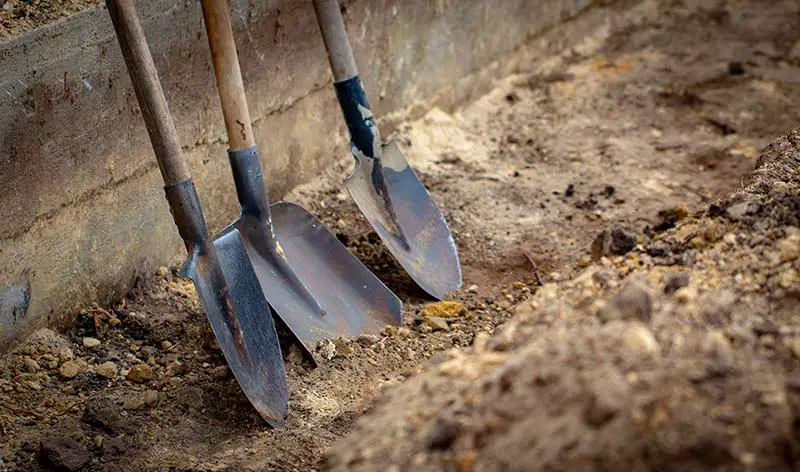 three shovels lined up against a brick wall