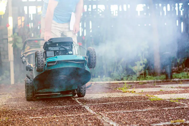 a smoking lawnmower being lifted up for inspection