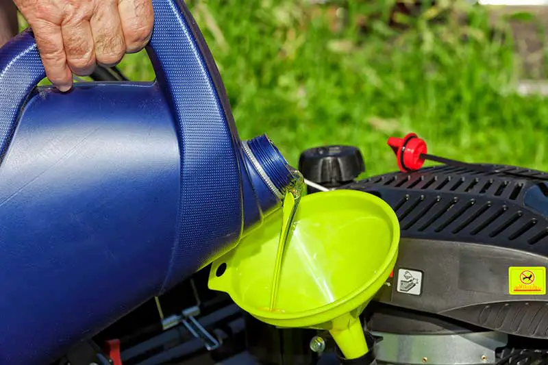 oil being funnelled into a lawn mower