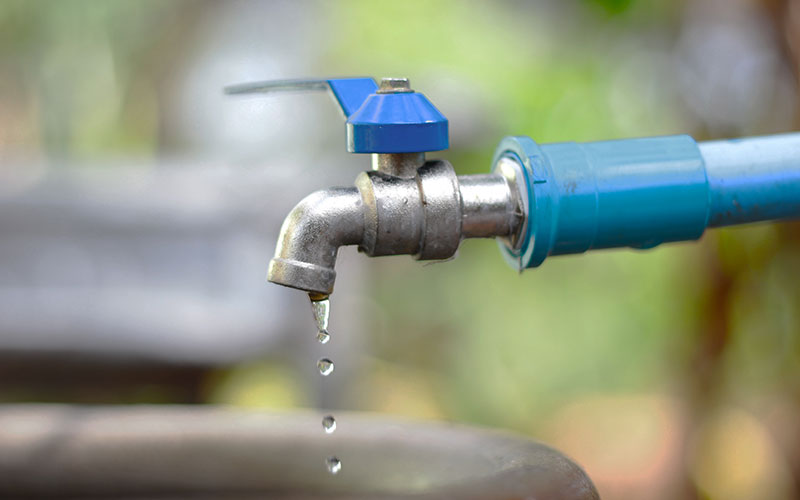 a faucet with a blue handle dripping water