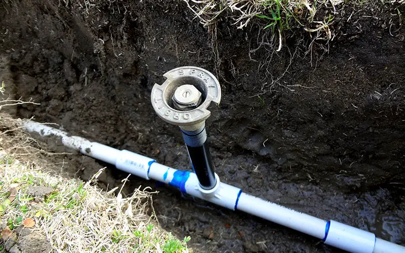 a sprinkler line and valve in dug-out trench