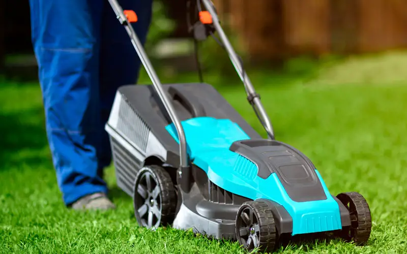 an electric lawn mower being walked along the grass