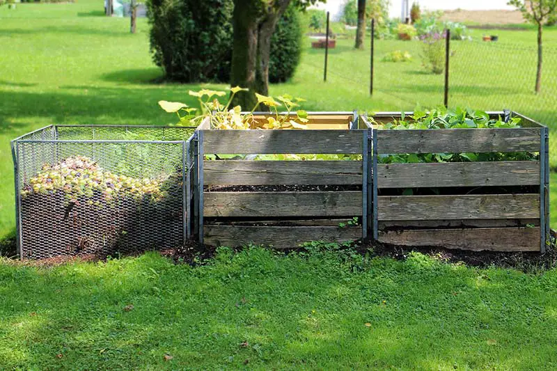a row of wire and wooden compost bins