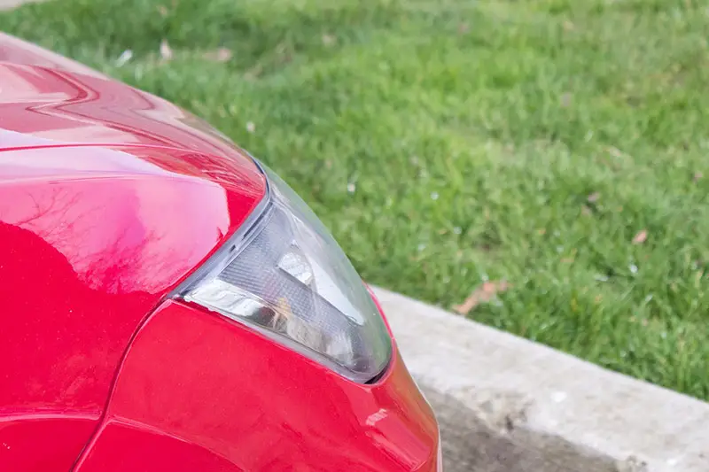 the front of a car next to a lawn