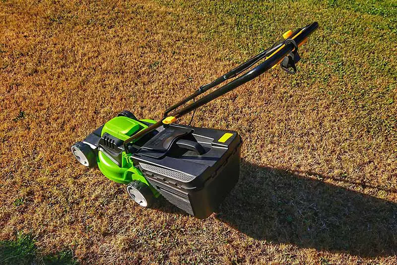 a lawn mower casting a shadow on a dry lawn