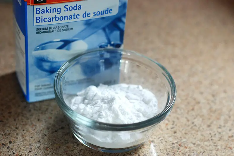 a bowl of baking soda next to its packaging